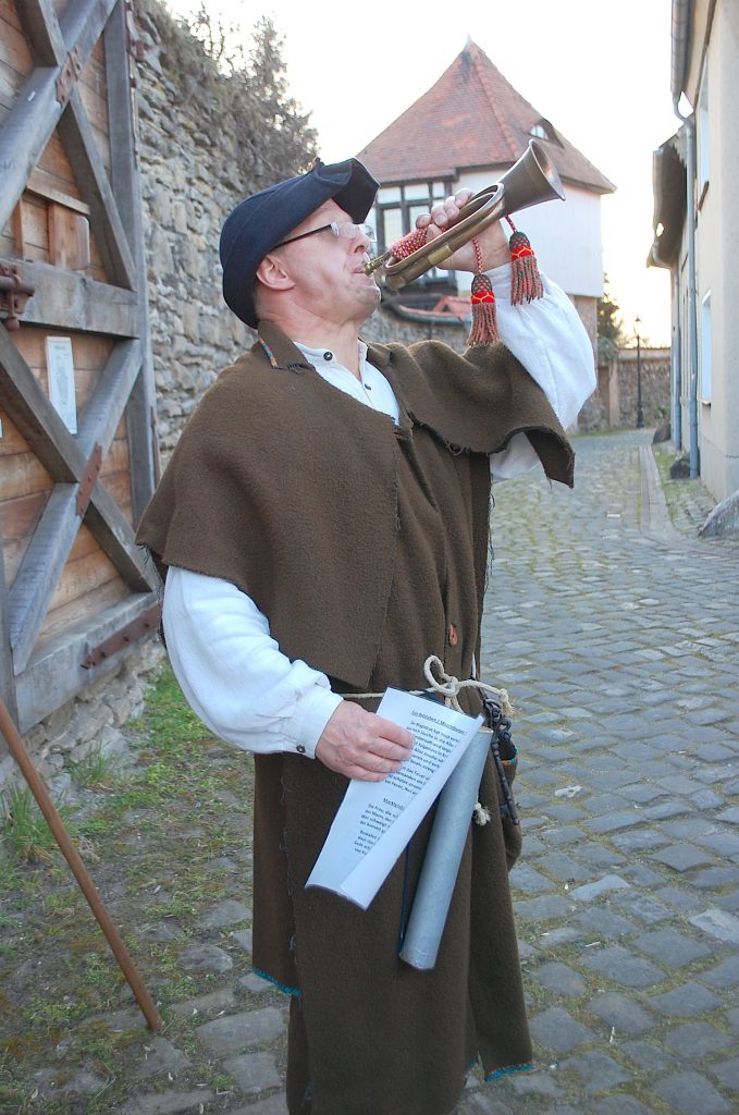 Nachtwächter mit Horn in einer historischen Gasse